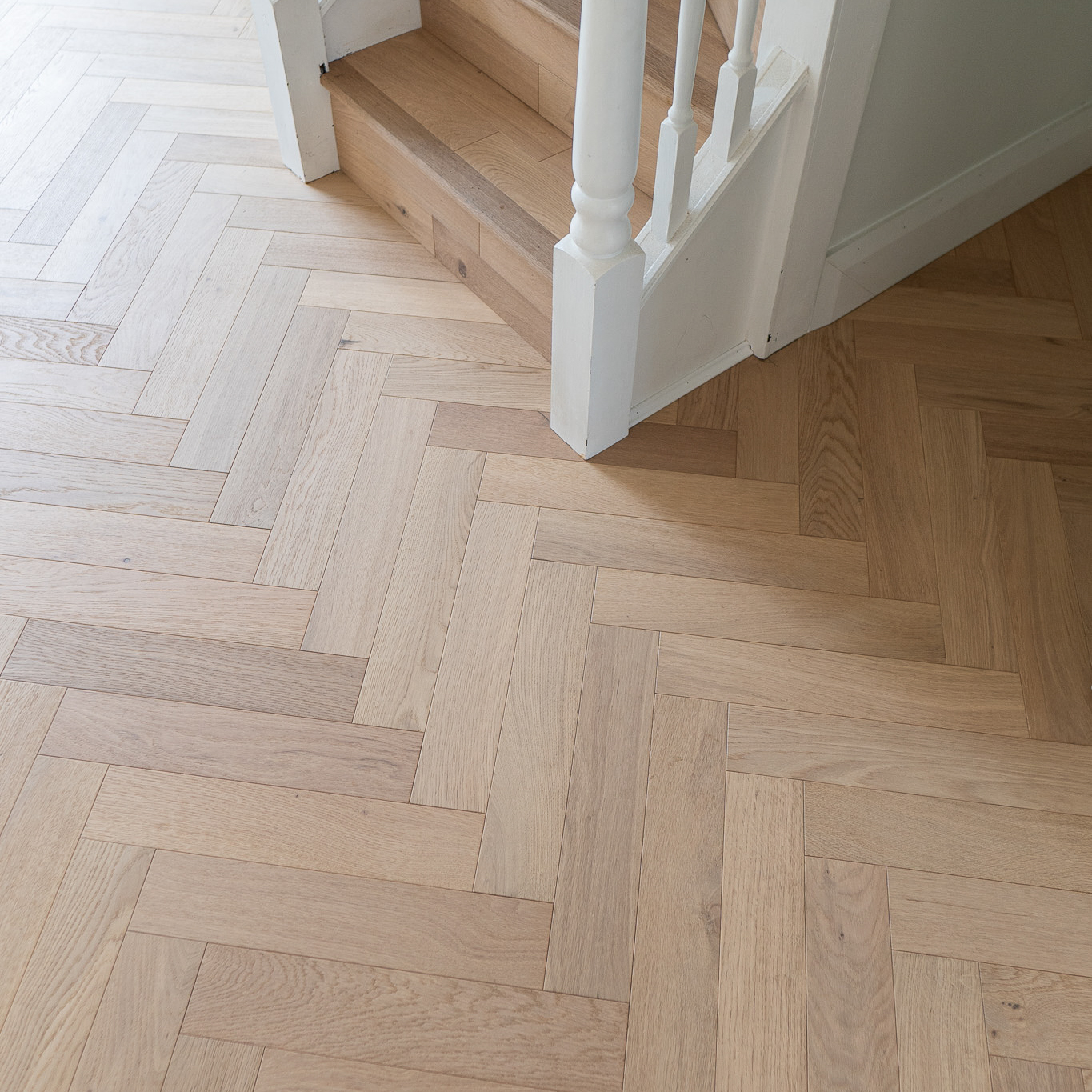 Invisible Light Oak Herringbone Engineered Wood Flooring with a subtle matte finish, showcasing light oak tones and a precisely arranged herringbone pattern