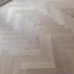 Invisible Light Oak Herringbone Engineered Wood Flooring with a subtle matte finish, showcasing light oak tones and a precisely arranged herringbone pattern